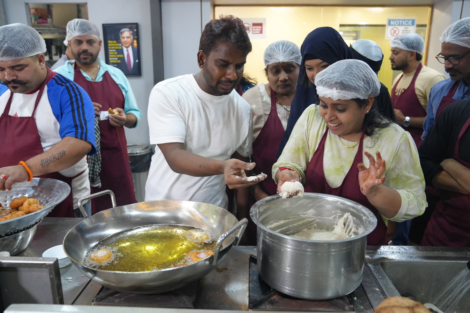 Chef Rajasekar guiding a student shaping dough beside the frying station